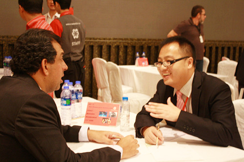 王春虎同学在向某位巴西采购商介绍自己。